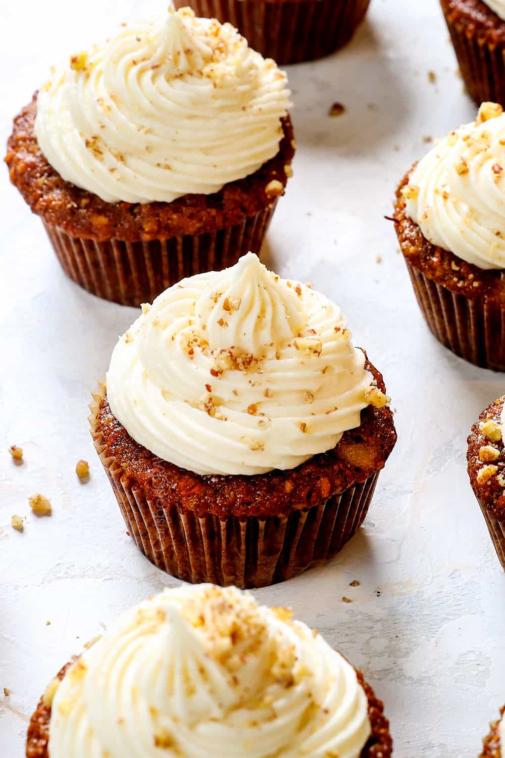 carrot cake cupcakes recipe with cream cheese frosting garnished with pecans