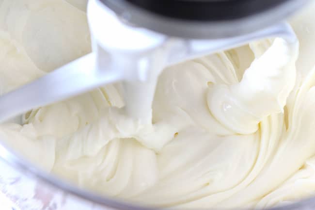 showing how to make carrot cake cupcakes by whipping cream cheese frosting in a stand mixer