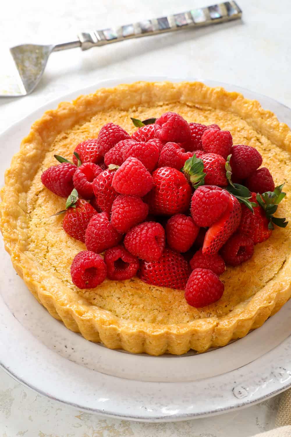 Coconut pie recipe with a pie crust, toasted coconut top, custard filling garnished by strawberries
