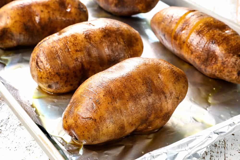 showing how to make Hasselback potatoes by coating sliced potatoes in olive oil and placing on a baking sheet