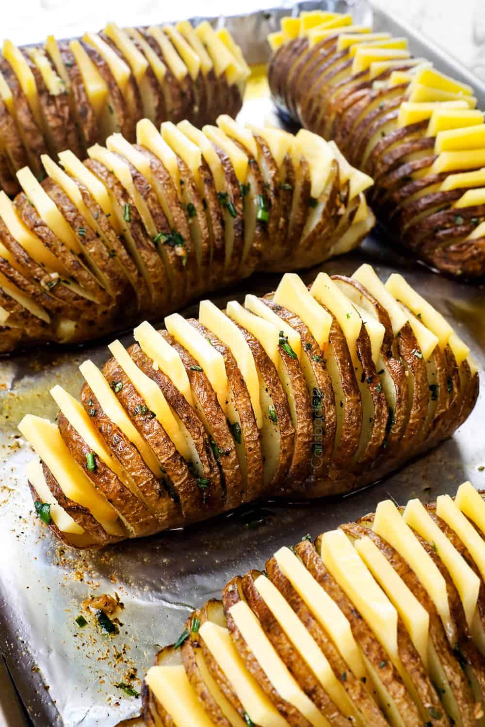 showing how to make Hasselback potatoes by adding slices of cheese in between the cuts