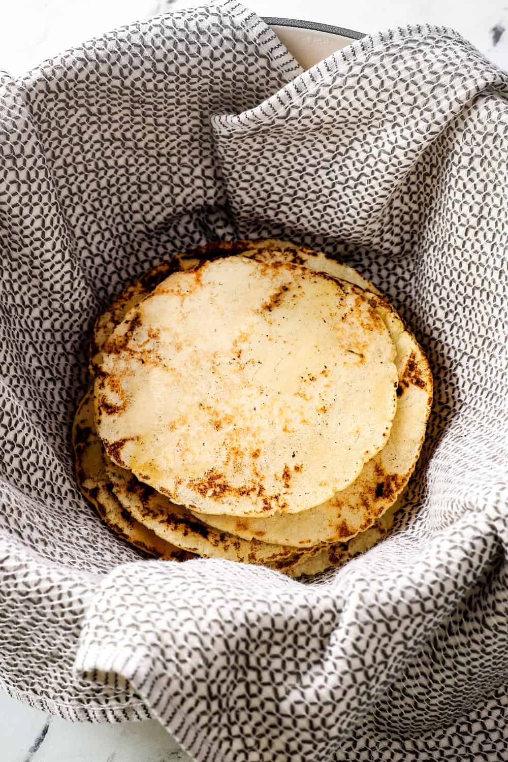a stack of corn tortilla recipe in a tortilla warmer showing how to keep tortillas soft and warm