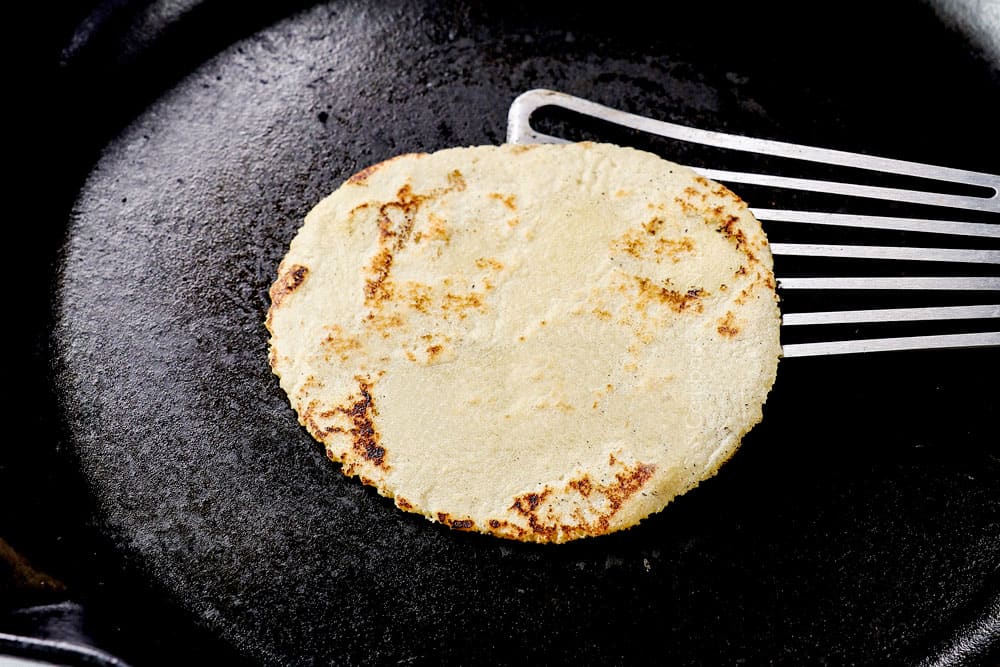 showing how to make homemade corn tortillas by cooking tortilla in a skillet until golden