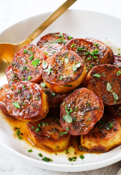 a bowl of melting butter potatoes garnished by fresh thyme
