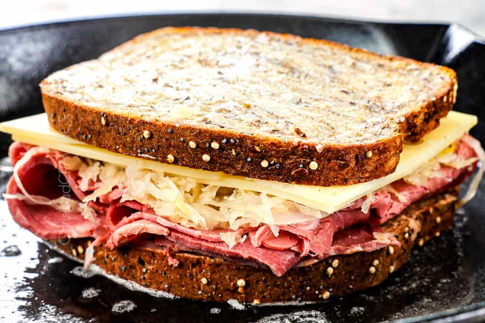 showing how to make Reuben sandwich by gilling in a cast iron skillet
