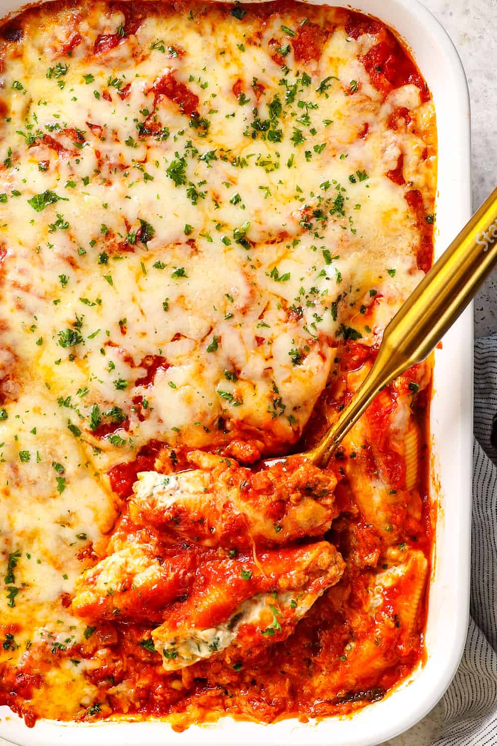top view of a spoonful of stuffed shells baked in a 9x13 baking dish