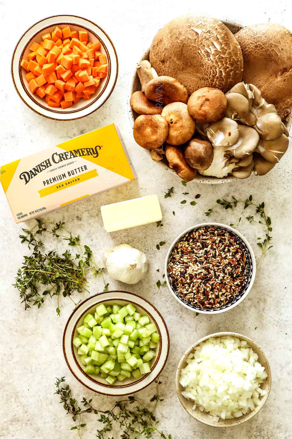 top view of showing how to make mushroom soup recipe with ingredients laid out:  mushrooms, butter, wild rice, carrots, celery, thyme and garlic