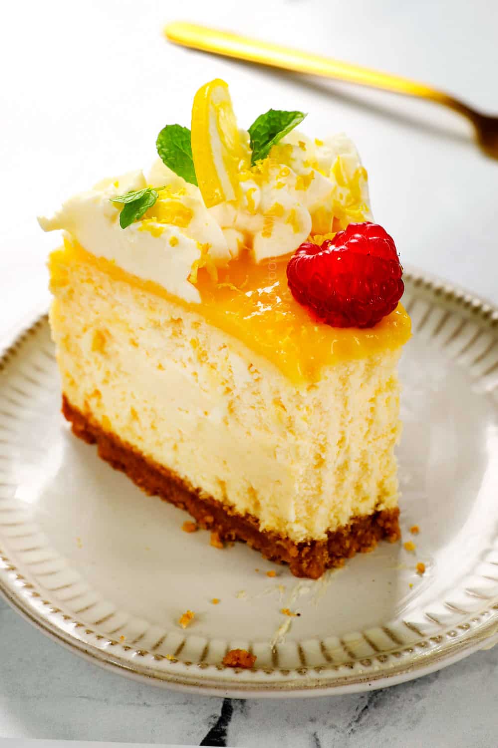 up close of a piece lemon cheesecake with a bite taken out showing how creamy it is