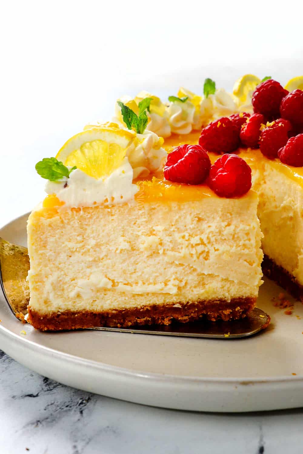 picking up a slice of lemon cheesecake garnished with raspberries