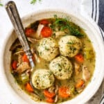 a bowl of matzo ball soup with matzo balls and chicken