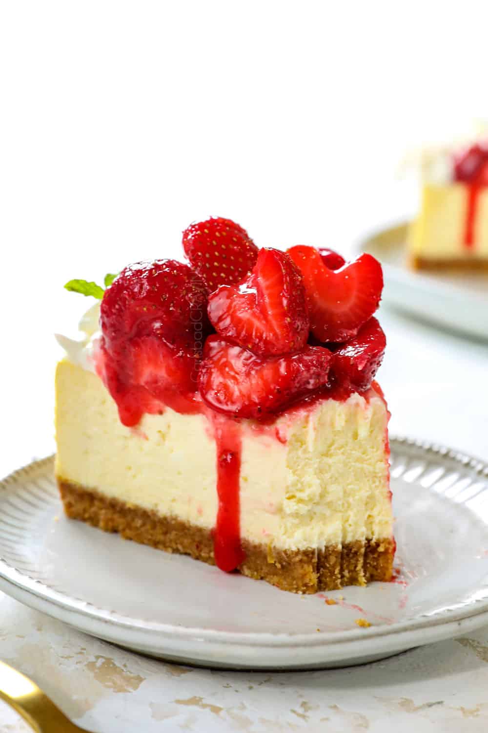 up close of a slice of strawberry cheesecake with a bite taken out showing how creamy it is