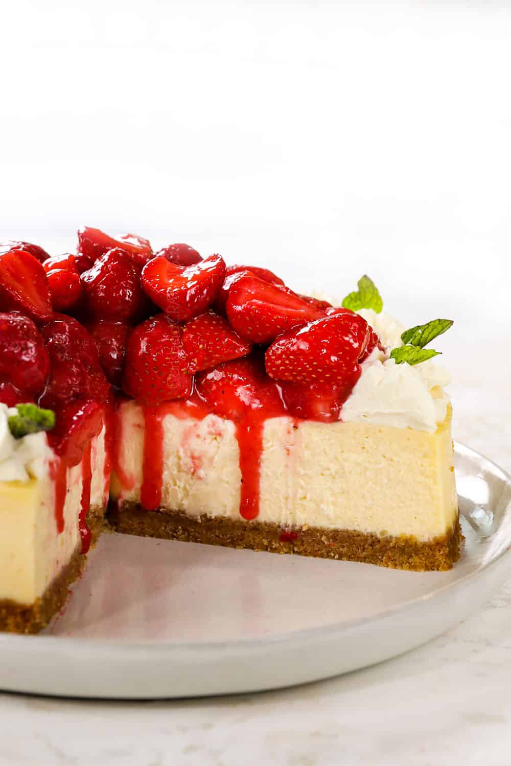 up close of strawberry cheesecake with a piece missing showing how creamy it is