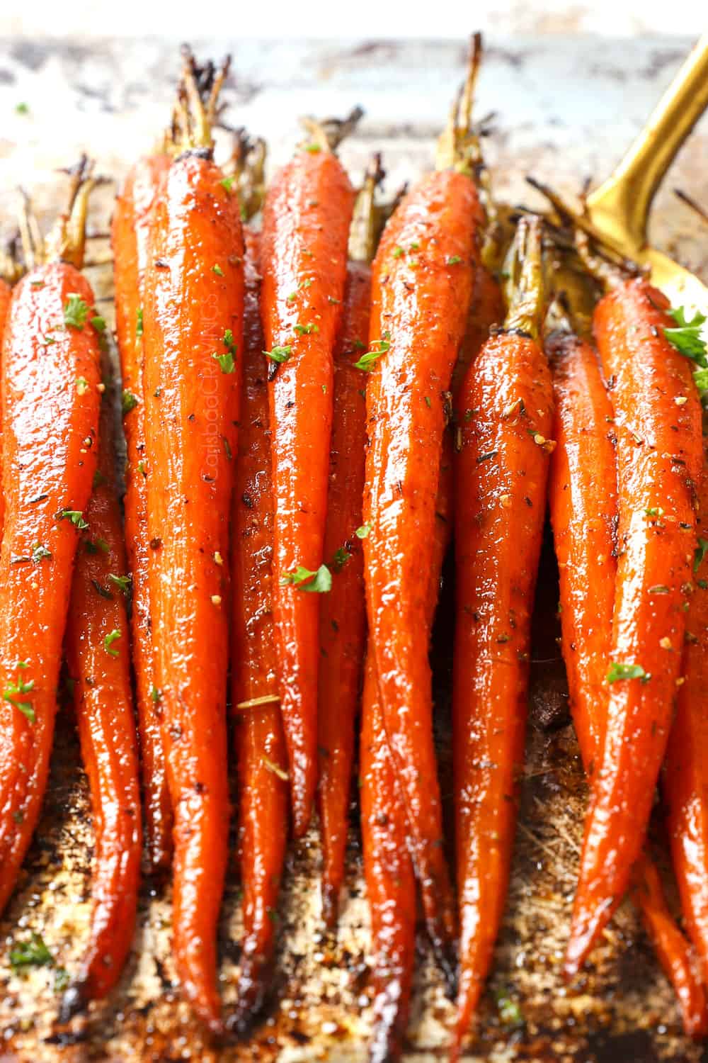 tossing oven roasted carrots in balsamic sauce
