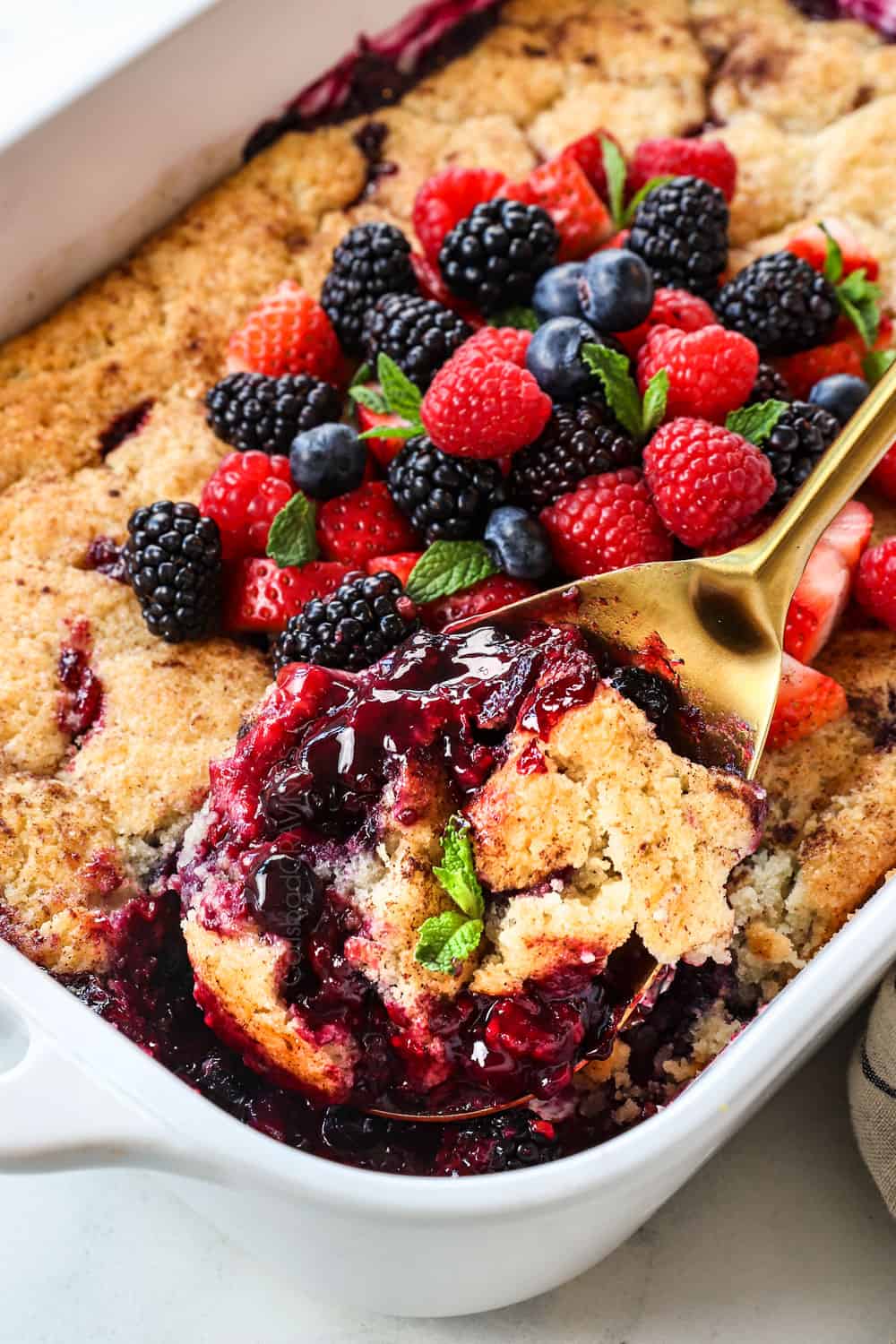 scooping up the mixed berry cobbler showing the juicy berries and golden biscuit topping