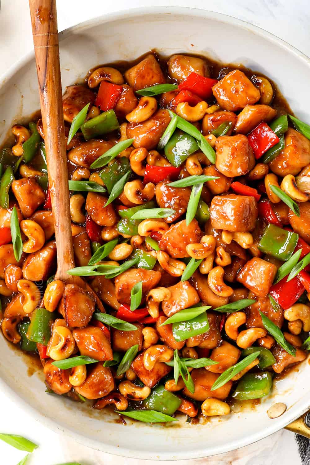 top view of cashew chicken stir fry in a skillet with cashews, chicken, bell peppers and green onions