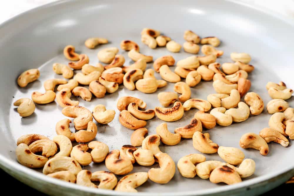 showing how to make cashew chicken stir fry by toasting cashews in a skillet
