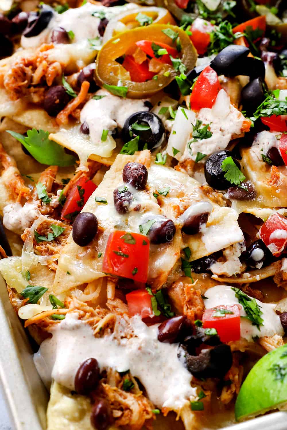 baked chicken nachos on a baking sheet with melted cheese