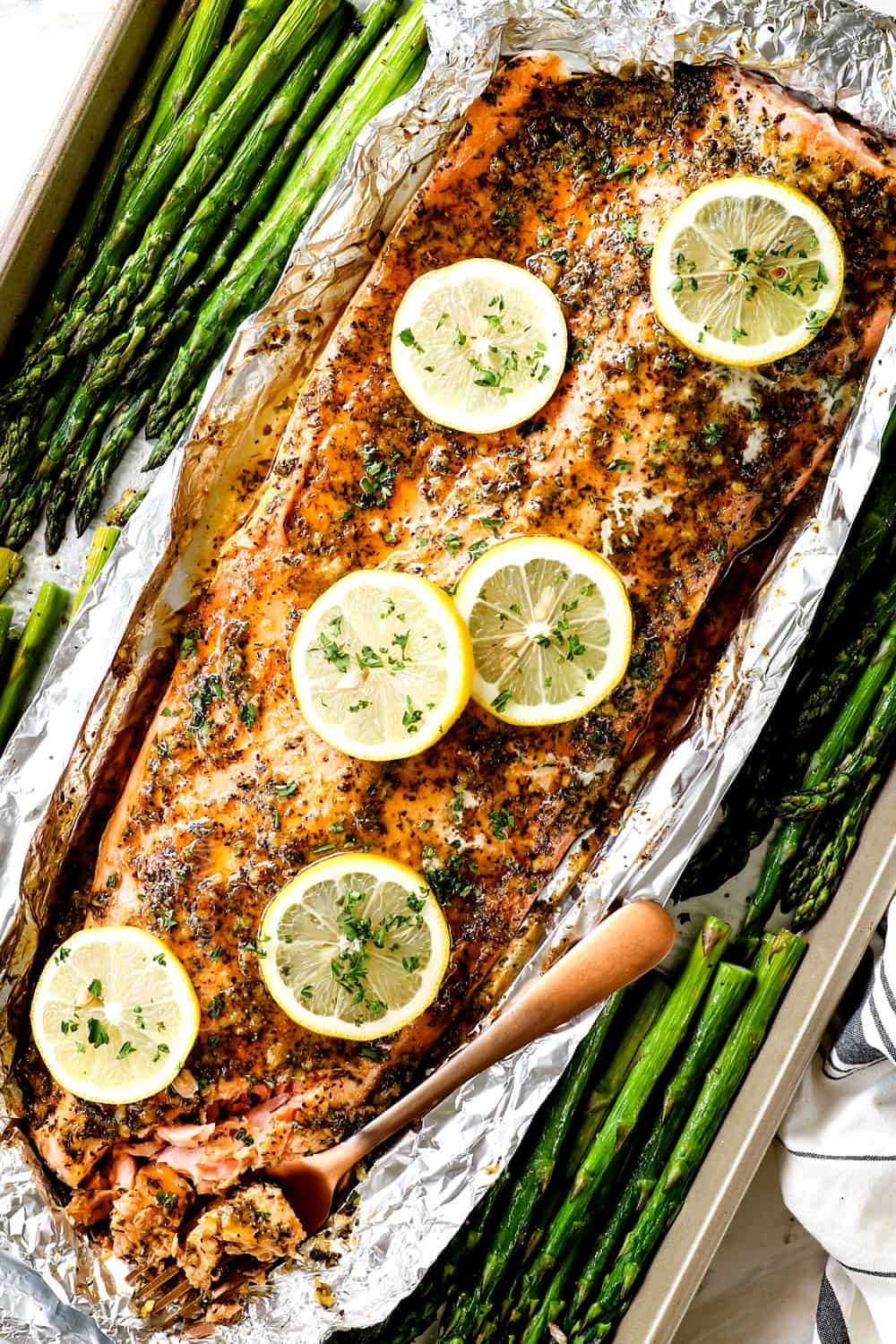 showing how tender bake lemon pepper salmon is by flaking with a fork