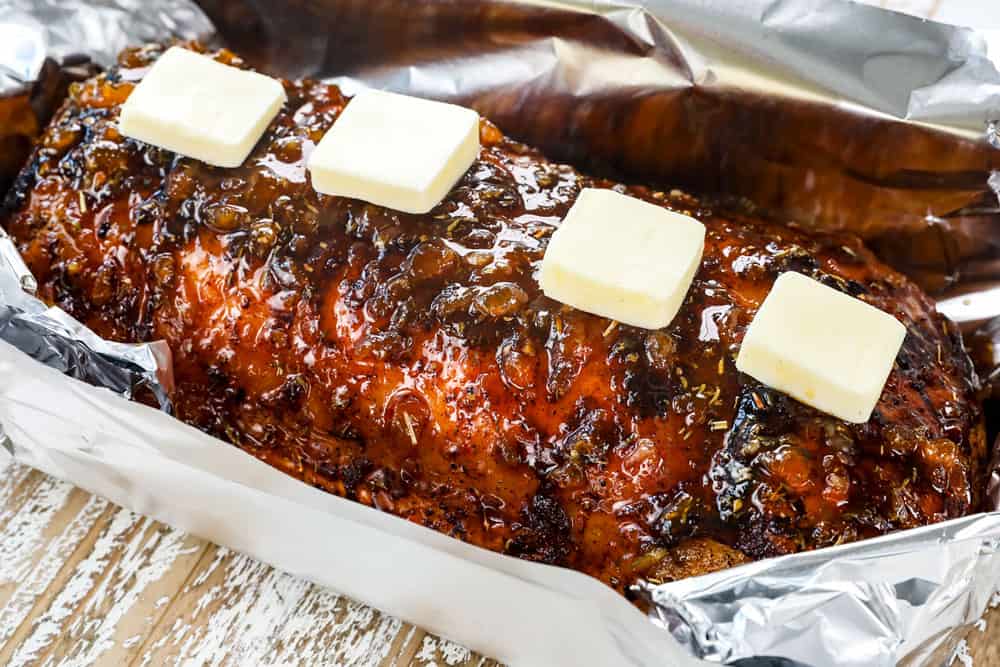 showing how to make pork loin roast recipe by adding pork loin to foil and topping with butter