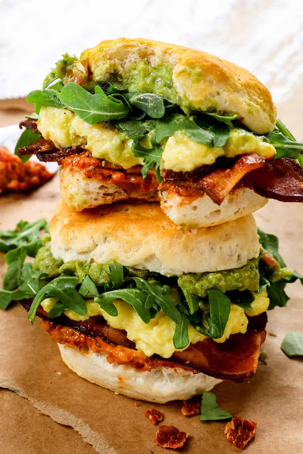 breakfast sandwiches with biscuits stacked on top of each other showing the cheesy eggs and bacon