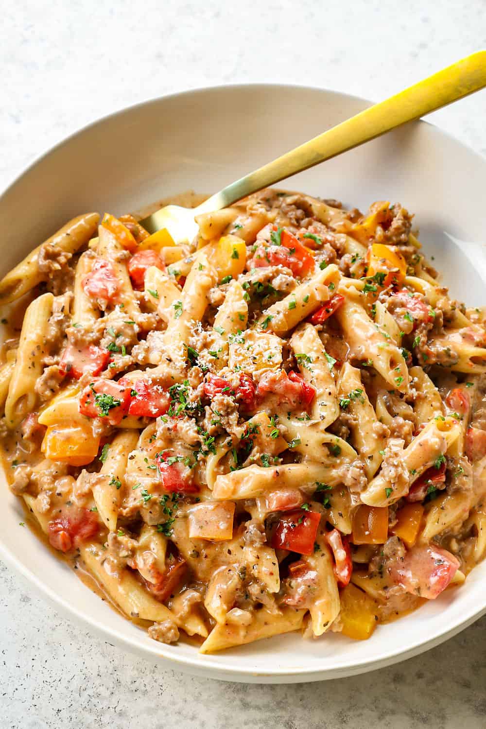 sausage pepper pasta with Italian sausage being served with Parmesan