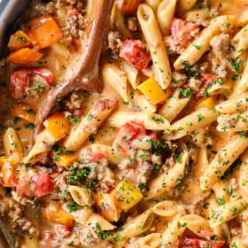 top view of sausage pepper pasta with Italian sausage in a skillet with cheesy cream sauce