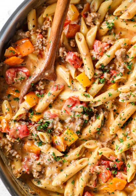 top view of sausage pepper pasta with Italian sausage in a skillet with cheesy cream sauce