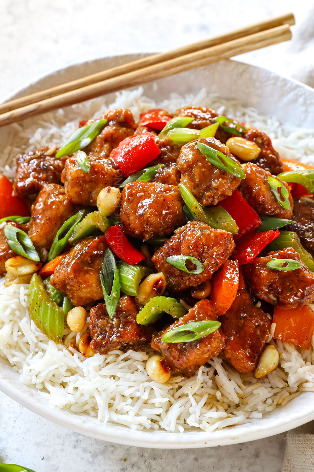 showing how to make Chinese black pepper chicken by adding to a bowl of rice
