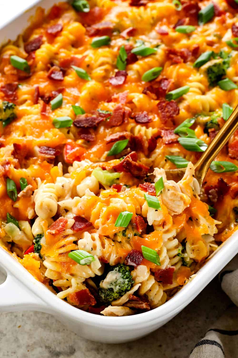 up close of serving chicken bacon ranch pasta casserole garnished with bacon and green onions