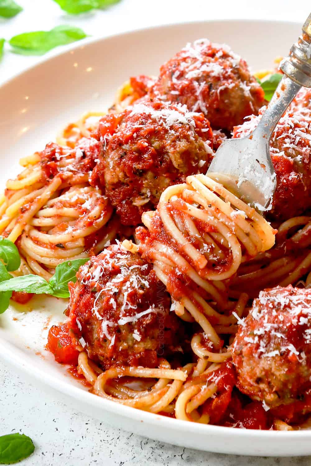 showing how tender and juicy Italian turkey meatballs are by picking up one with a fork