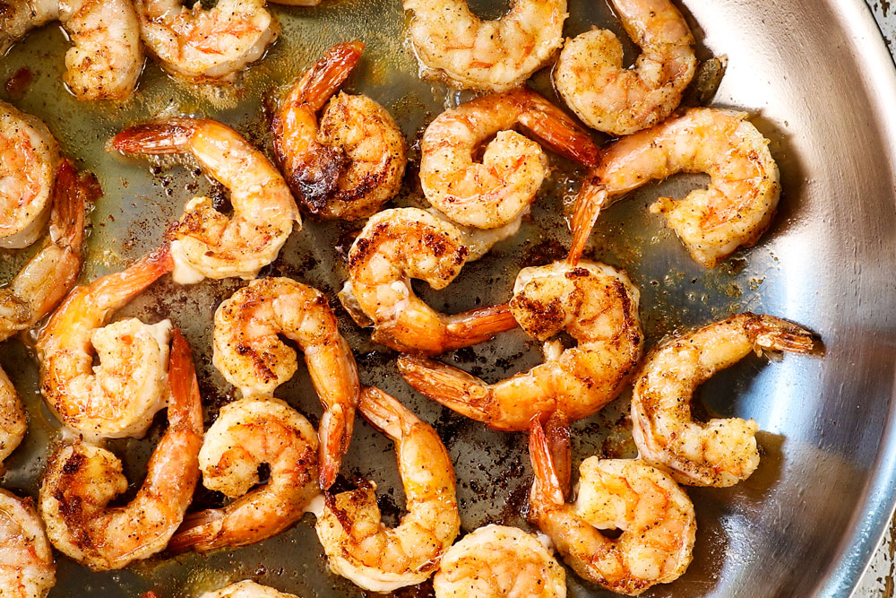 showing how to make Tuscan shrimp by searing shrimp in a skillet until opaque and golden