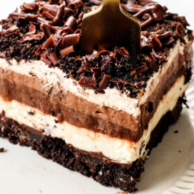 a fork taking a bite of of a slice of chocolate lasagna with Oreos and chocolate pudding