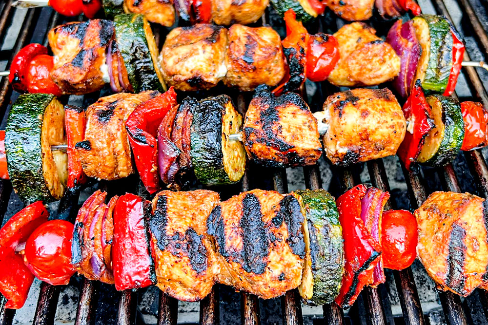 showing how to make Greek Chicken Kabobs by grilling chicken kabobs on a barbecue grill