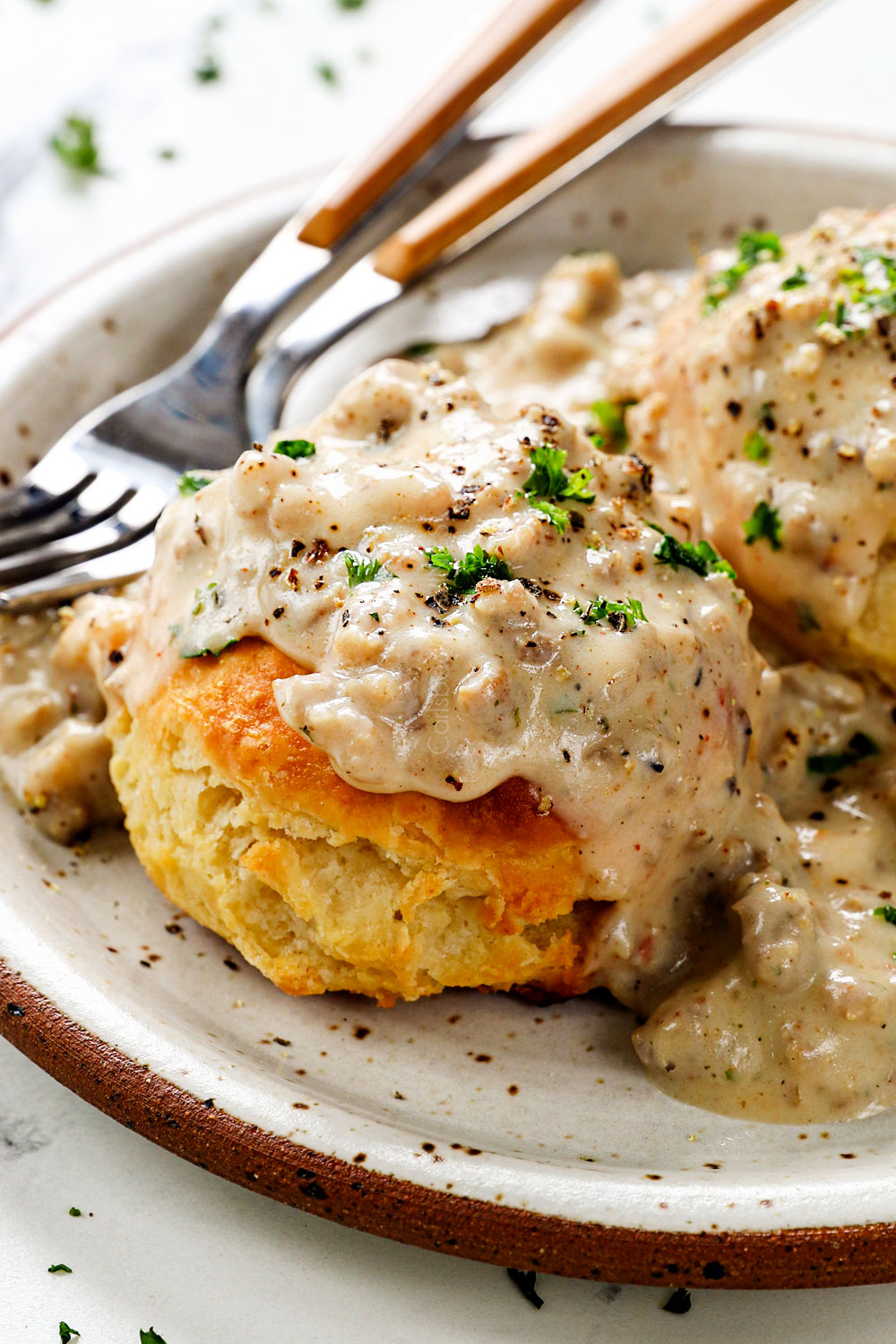 up close of sausage gravy and biscuits showing how fluffy and tall the biscuits are