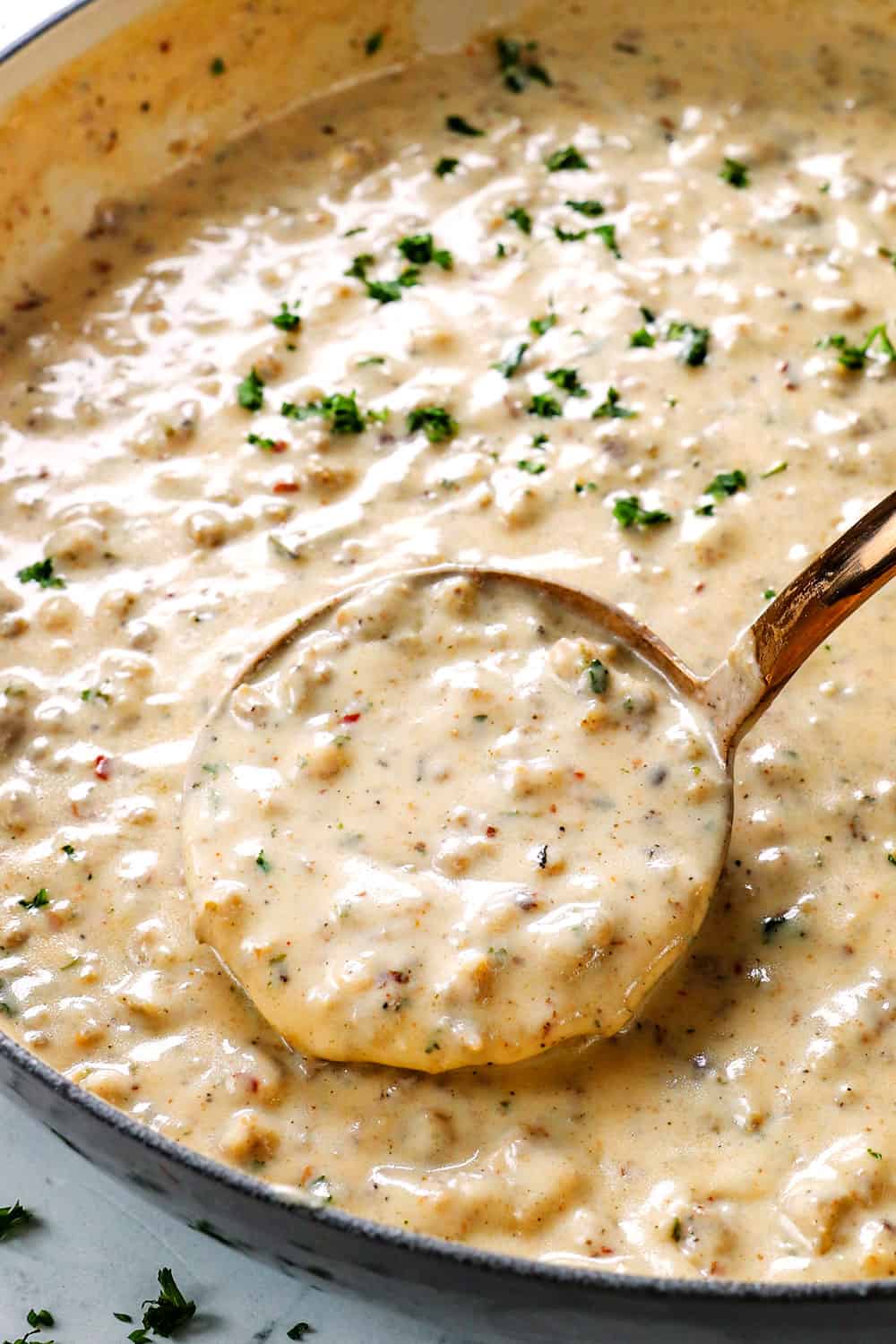 showing how to make biscuits and gravy recipe by simmering sausage gravy until thick and creamy