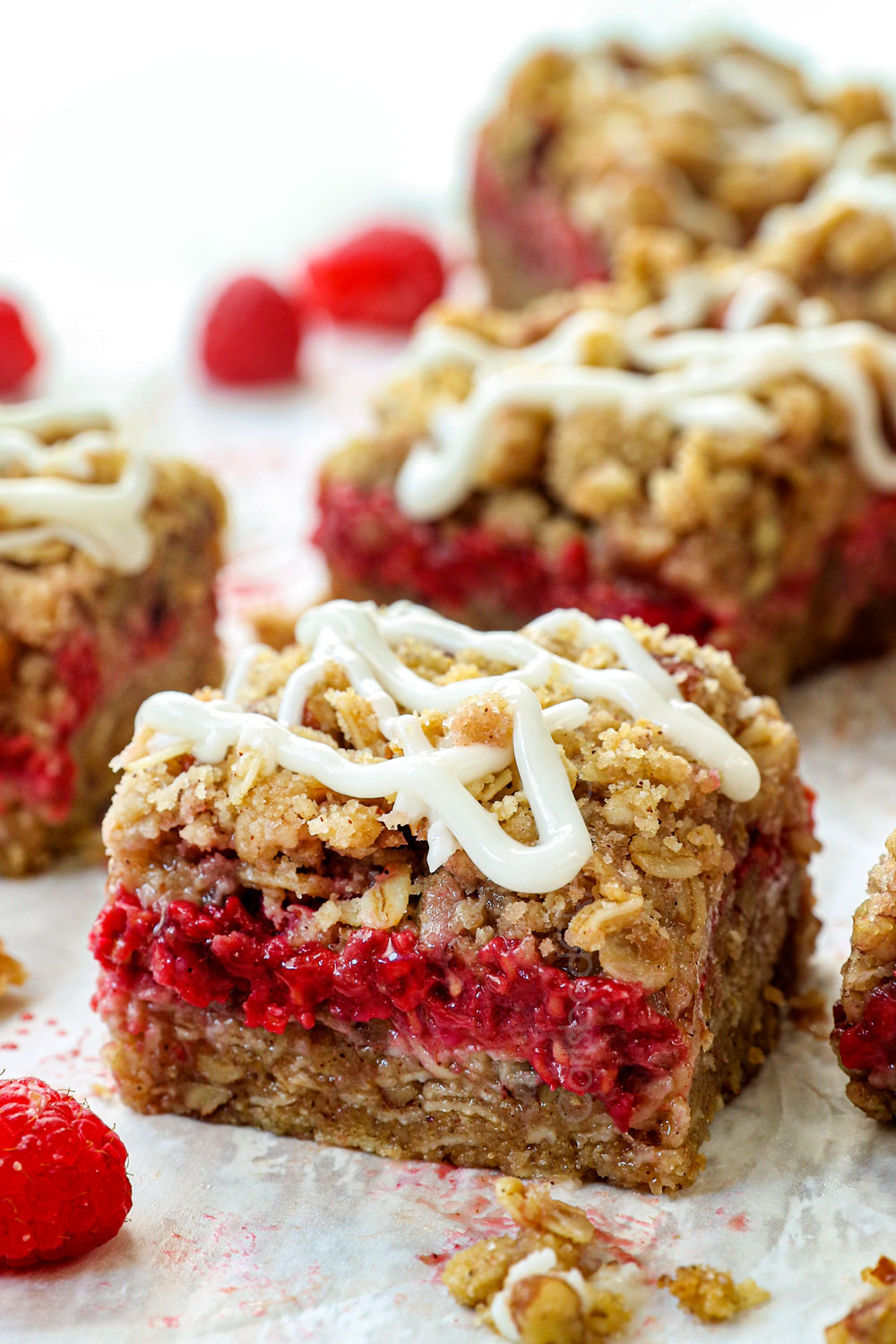 up close of raspberry oatmeal bars with icing showing how thick and chewy they are