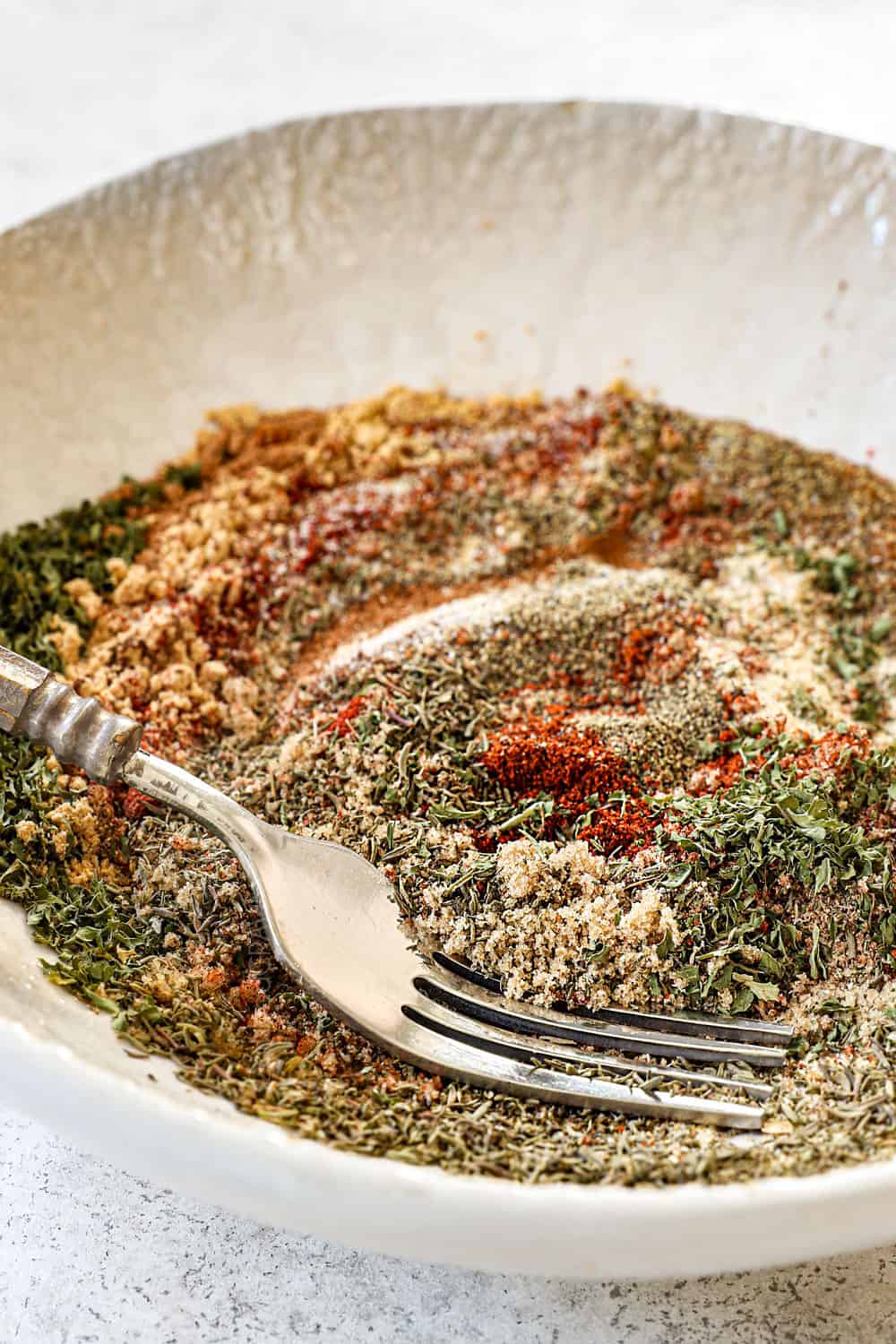 side view of making Jamaican jerk seasoning recipe by whisking the spices in a bowl