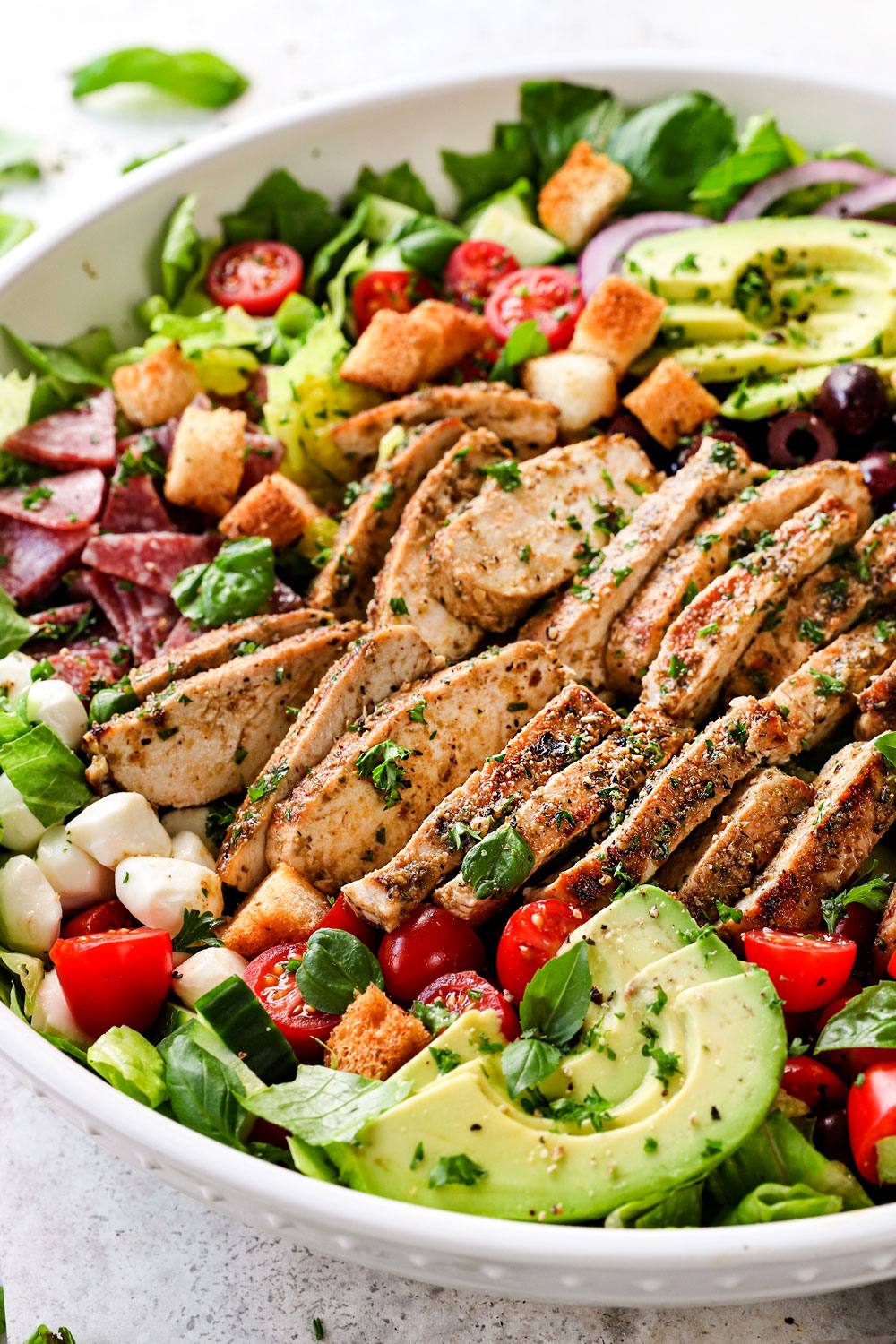 serving Mediterranean chicken salad recipe in a bowl garnished by parsley