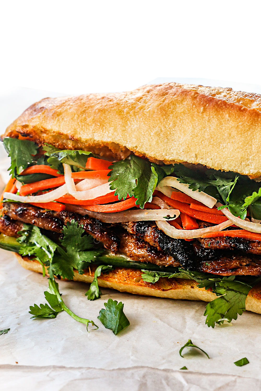 up close of banh mi sandwich with pork, pickled vegetables, cilantro, cucumber and jalapenos