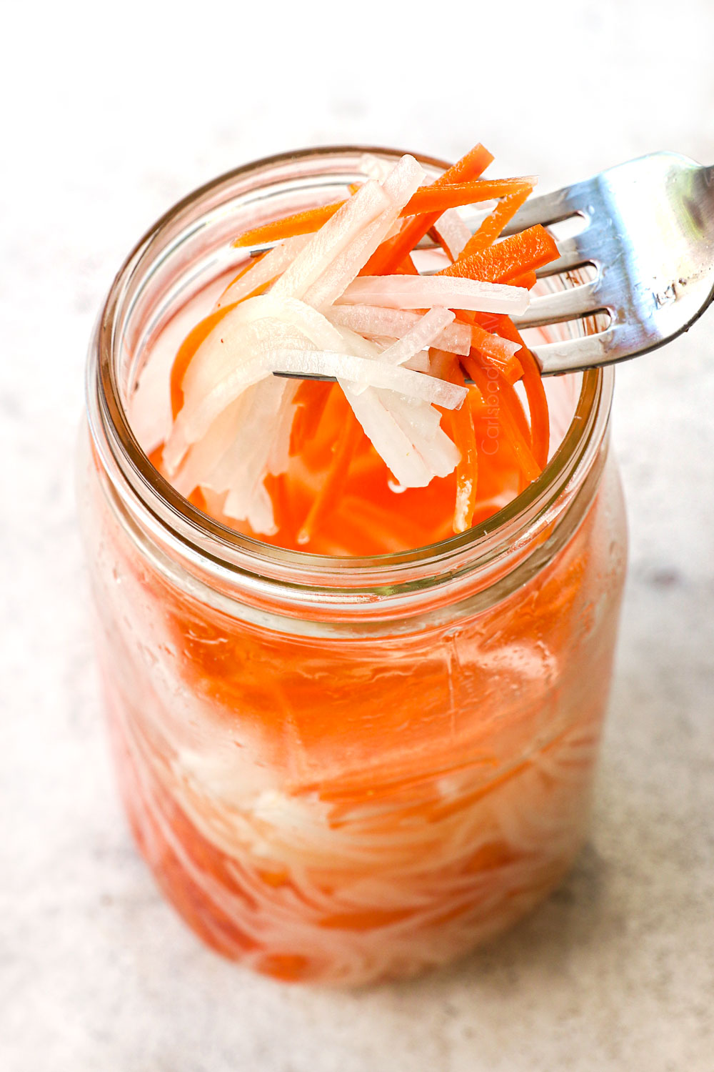 showing how to make banh mi sandwich recipe by pickling matchstick carrots and daikon in rice vinegar and sugar