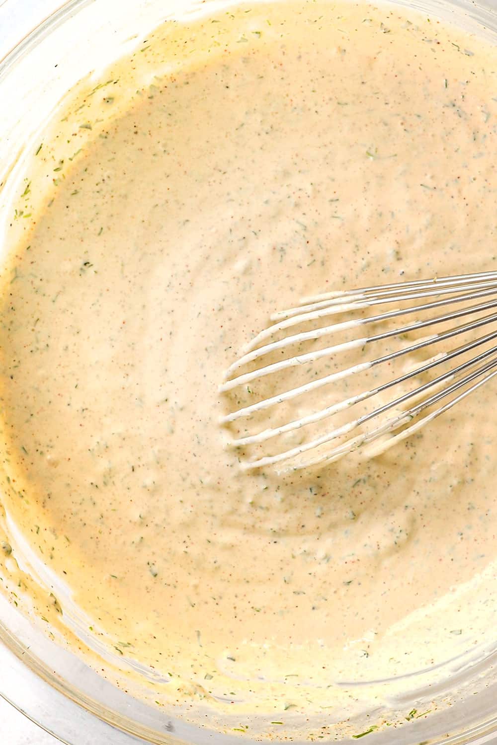 showing how to make ranch dressing recipe by whisking the ingredients together in a bowl