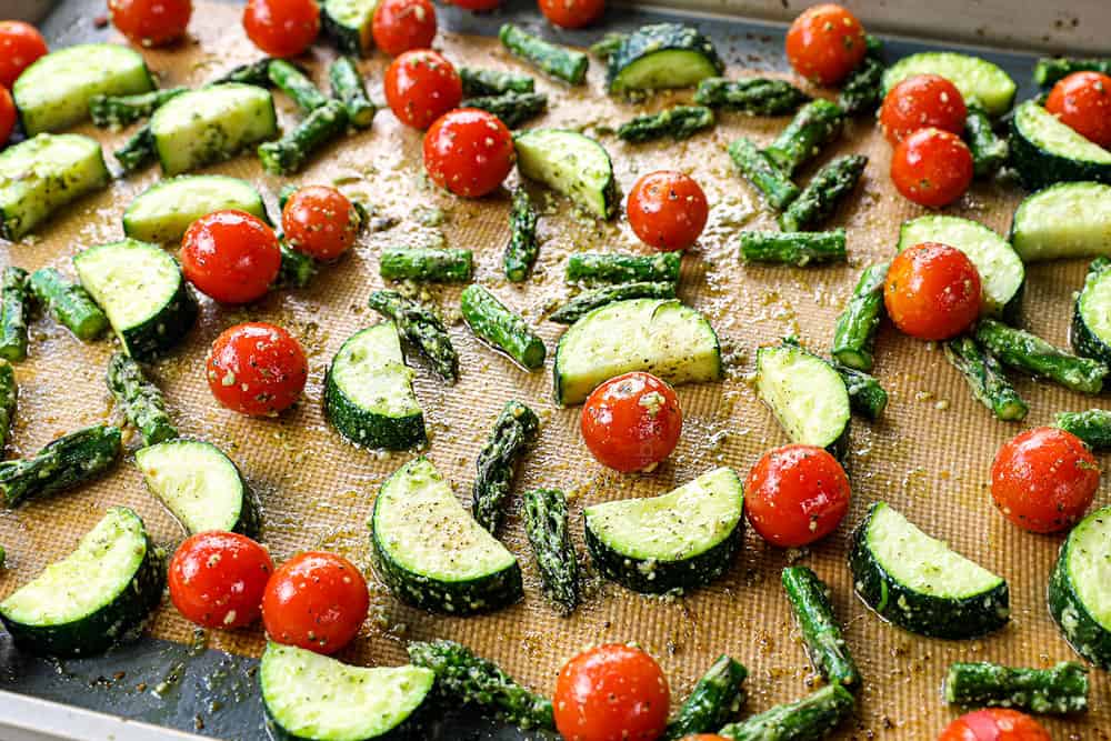 showing how to make pesto pasta recipe by roasting vegetables on a baking sheet