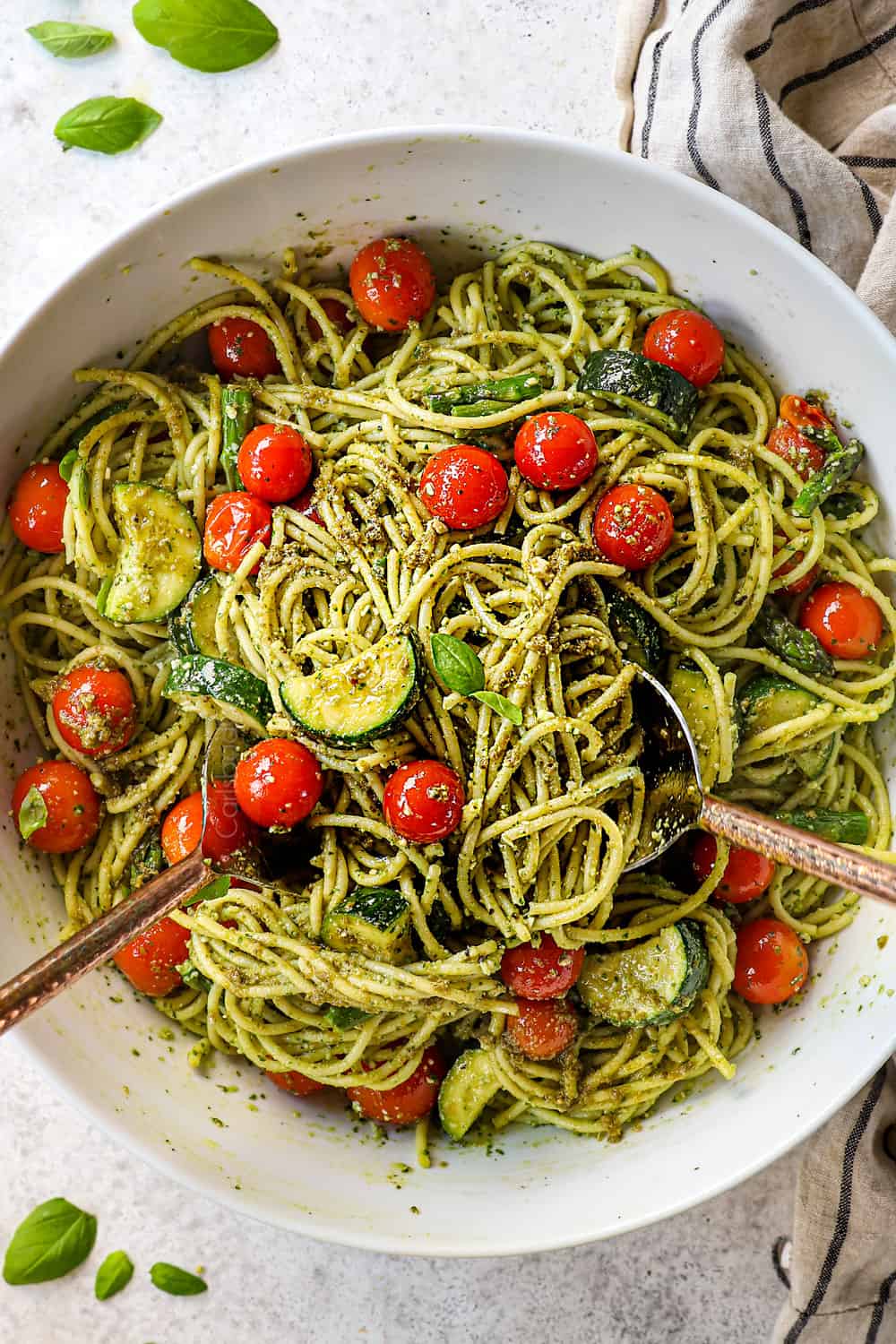 showing how to make pesto pasta recipes by tossing pesto, pasta and vegetables together