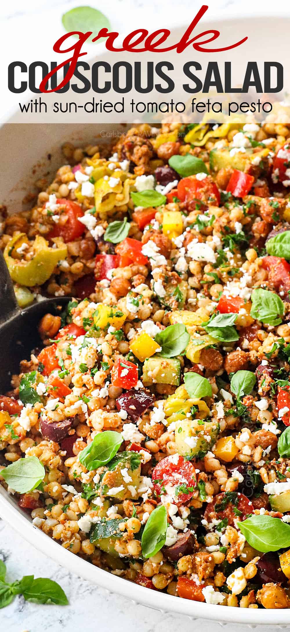 a large bowl of Greek couscous salad recipe with tomatoes, olives, cucumbers, red onions, bell peppers, feta