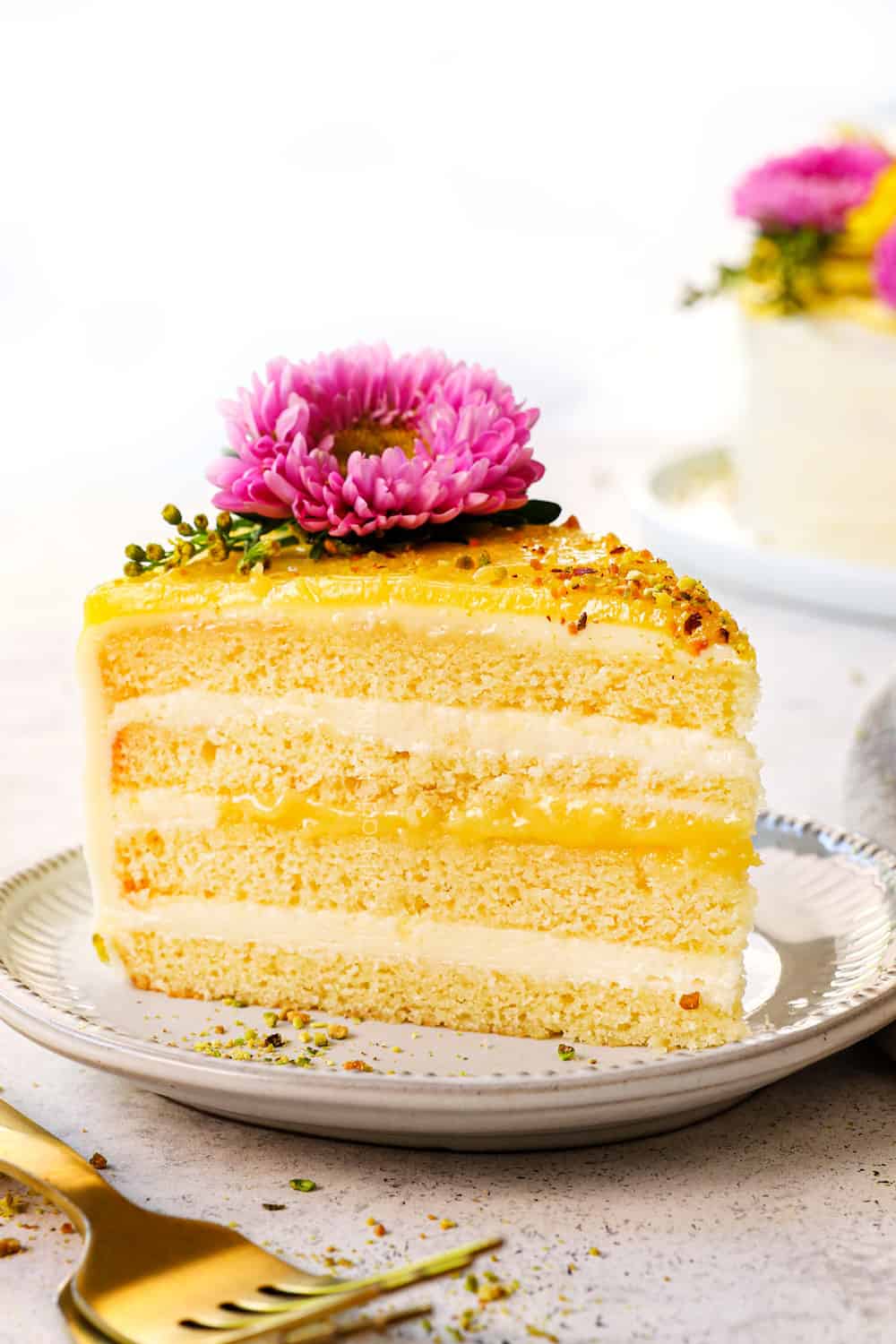 a slice of lemon cake on a plate showing the moist cake layers and lemon curd layers
