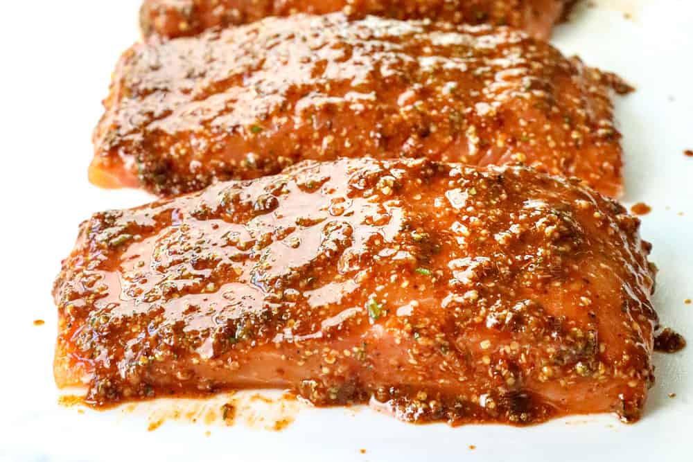 showing how to make cedar plank salmon recipe by adding marinade to salmon