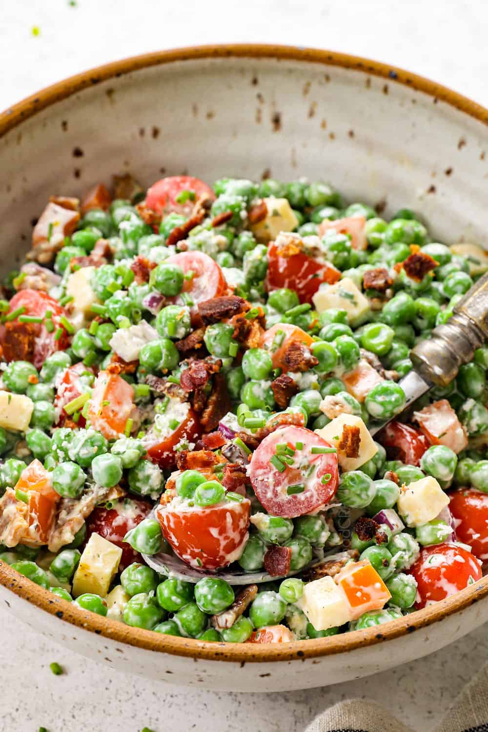 up close of a spoon eating pea salad with green peas and bacon