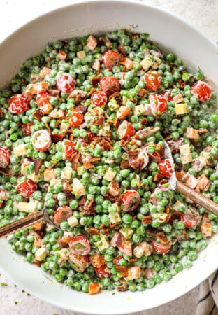 showing how to make pea salad recipe by tossing peas, bacon, cheese, onions, and creamy dressing together in a bowl