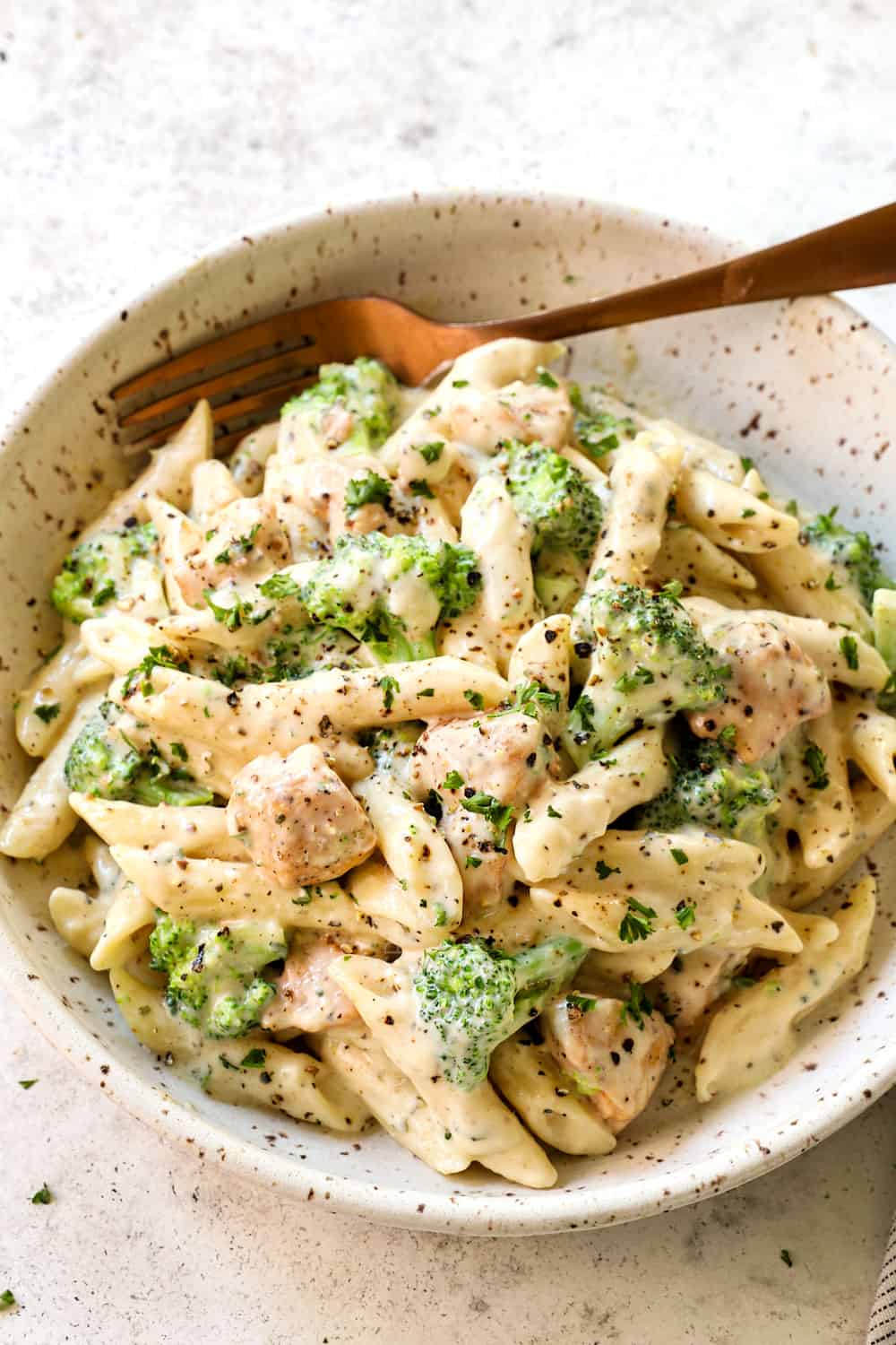 chicken and broccoli Alfredo with penne in a bowl garnished by Parmesan