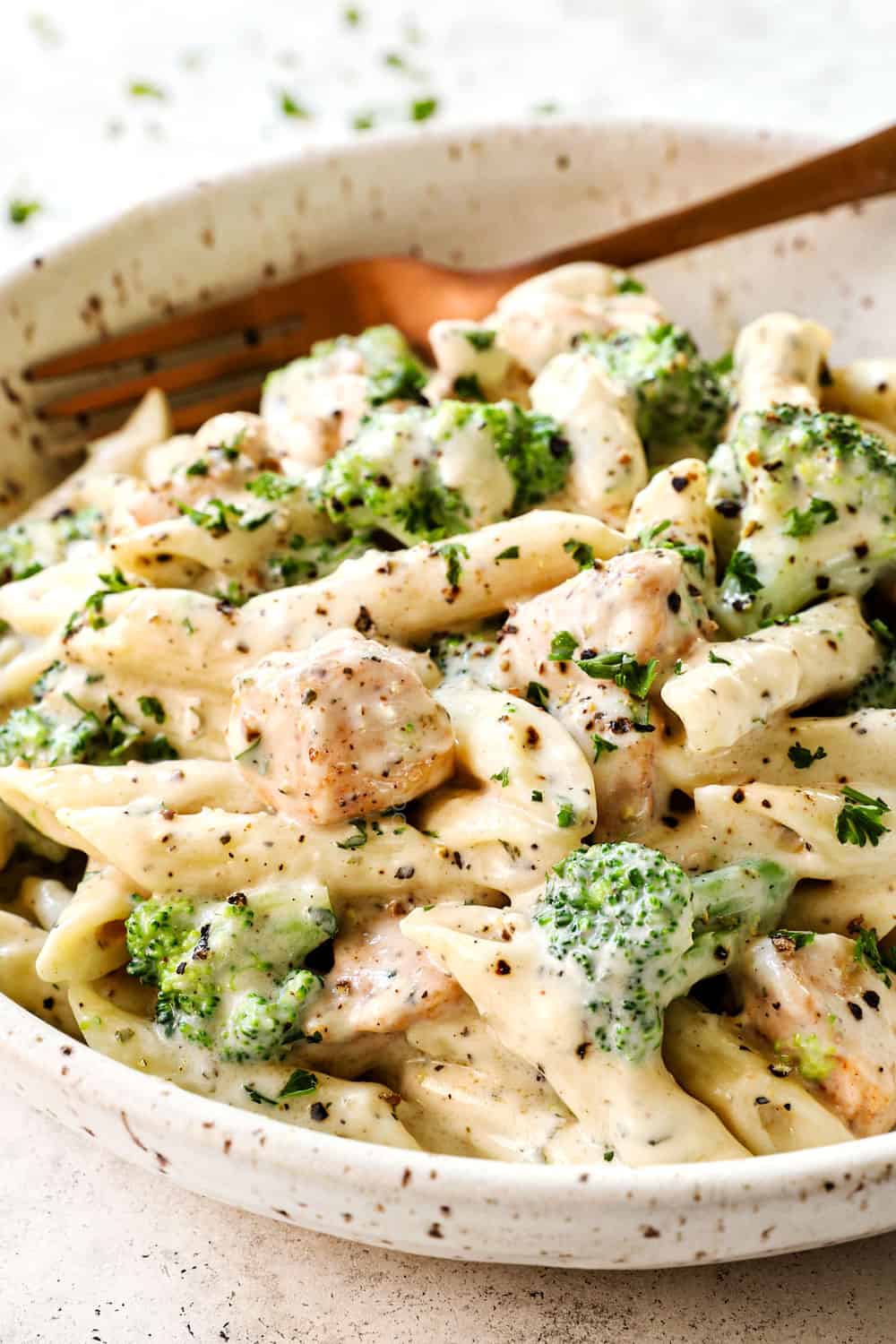 chicken and broccoli Alfredo with penne in a bowl garnished by Parmesan